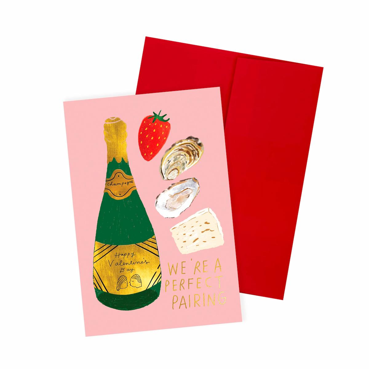 Greeting card with champagne bottle, strawberry, oysters, and cheese illustration on pink background with red envelope.