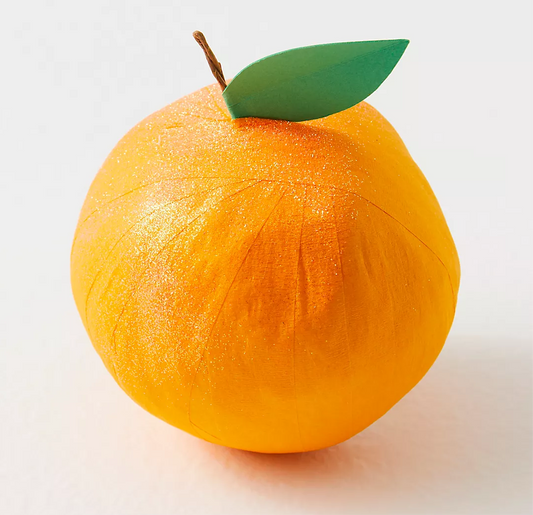 A crepe paper orange with a green leaf on top, designed as a surprise gift with layers of ribbon and a vintage-inspired keepsake inside.