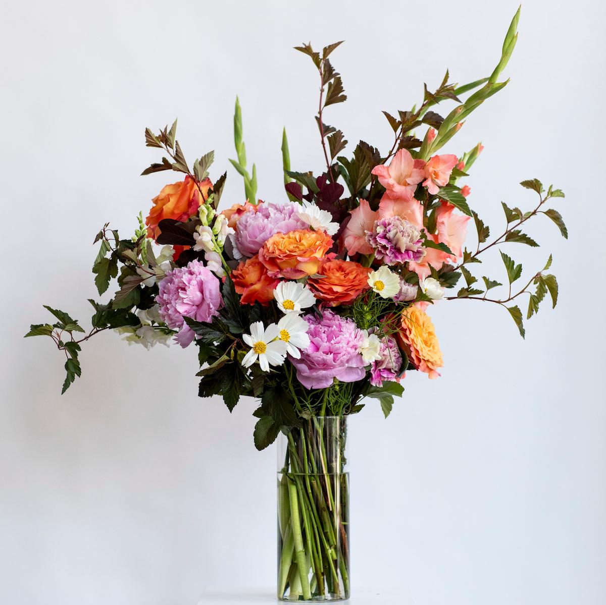 colorful boutique of flowers on a white background in a clear tall vase