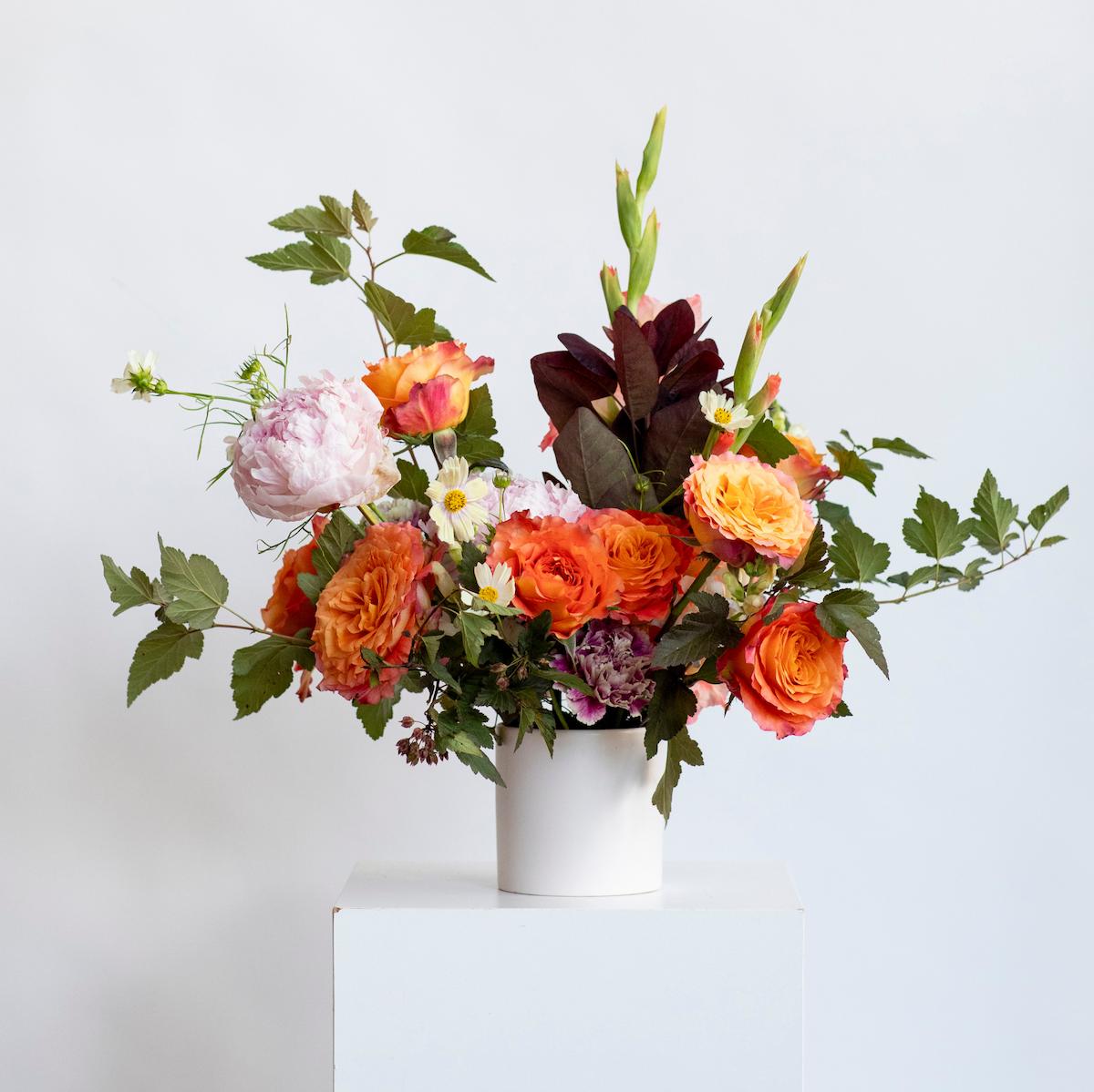 colorful floral centerpiece on a white background and a white vase
