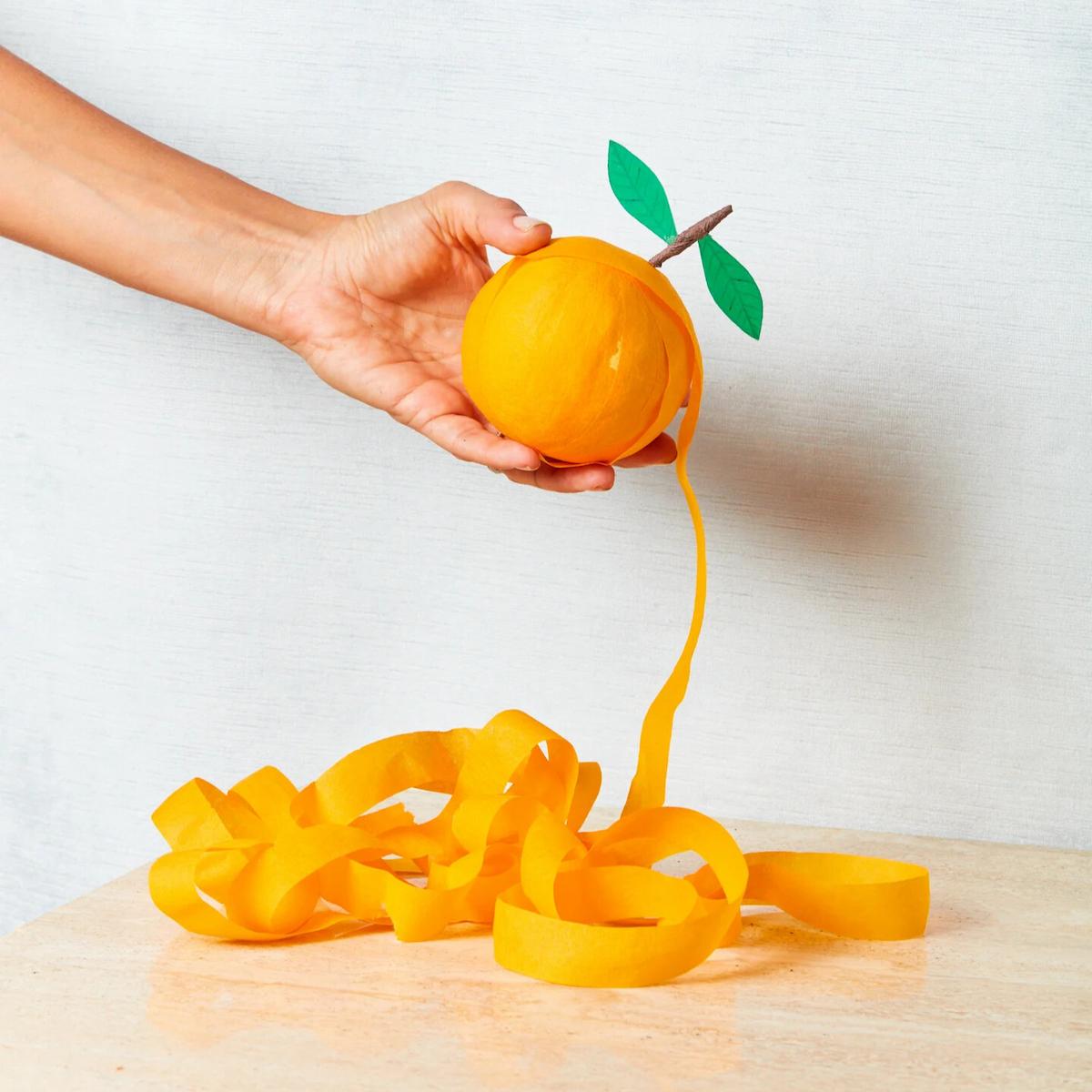 Hand holding a yellow ball with a string attached, on a light background