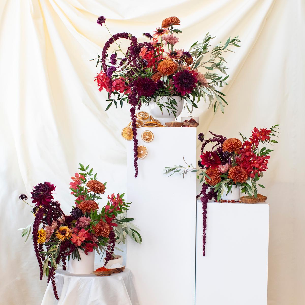 Decorative floral arrangements on a white tablecloth with a beige curtain background