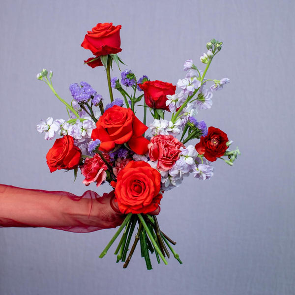 Bouquet of red and pink roses with greenery against a gray background
